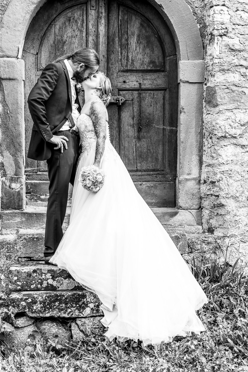 Brautpaar steht küssend auf einer alten Steintreppe