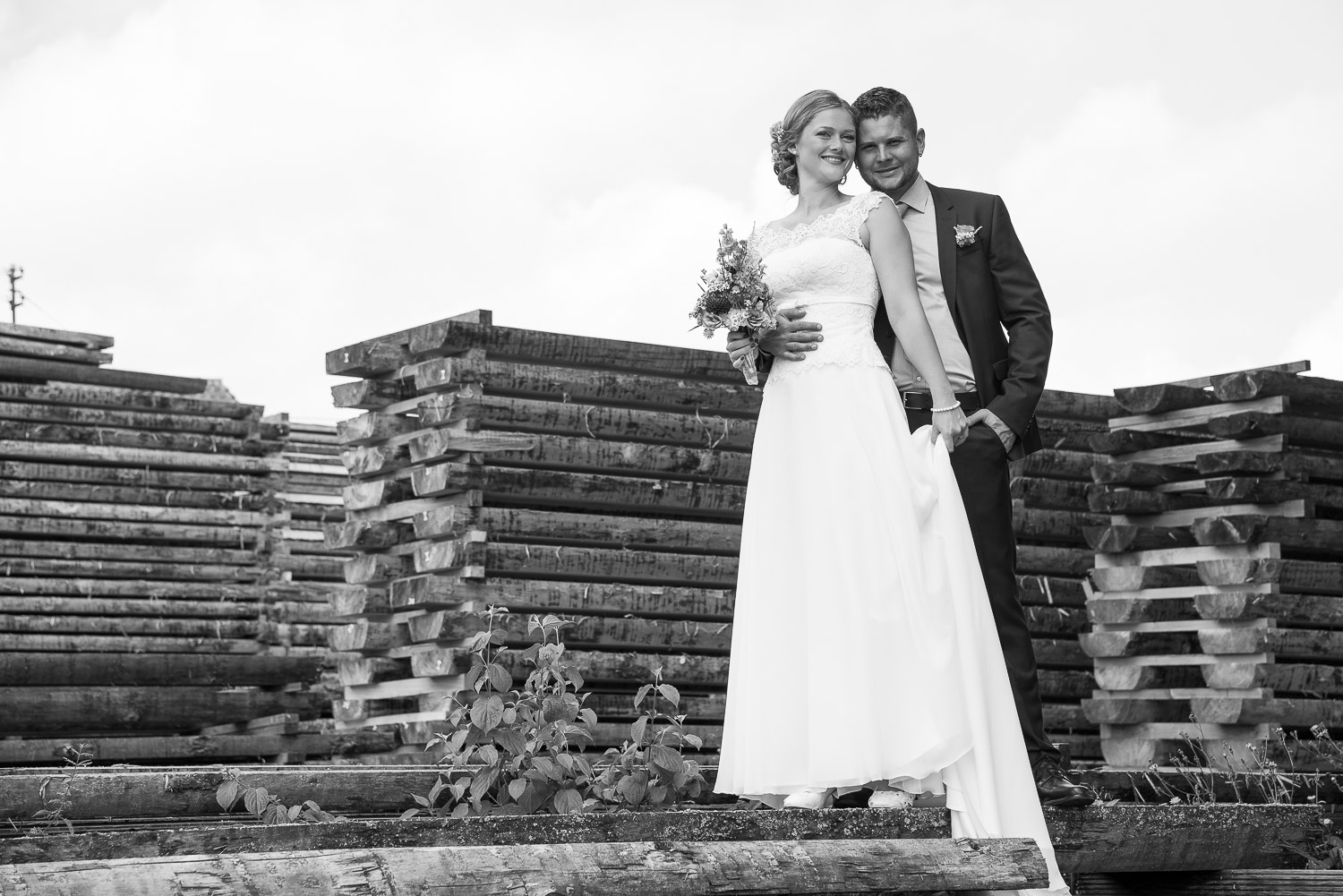 Brautpaar steht auf Holzstapel
