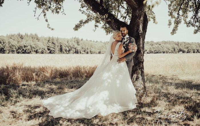 Hochzeitspaar-steht-unter-einem-Baum