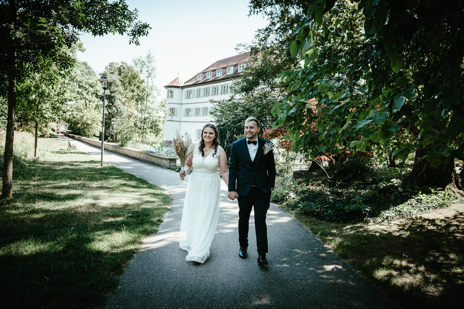 Brautpaar-geht-hand-in-hand-durch-Park-am-Wasserschloss-Bad-Rappenau