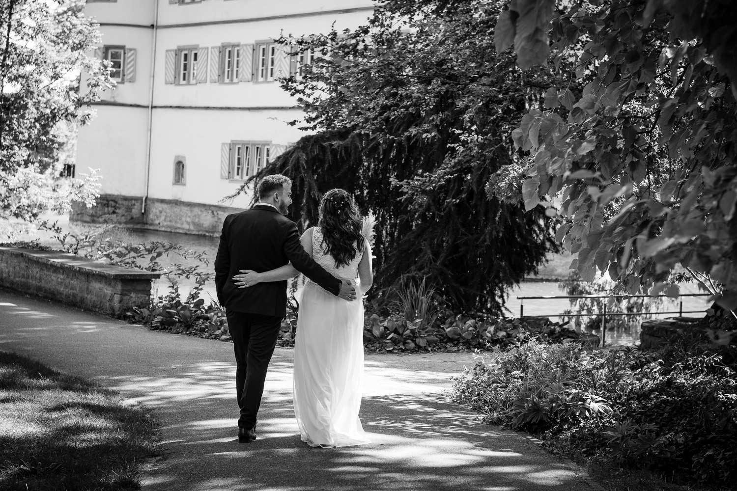 Brautpaar-geht-umarmt-durch-Park-am-Wasserschloss-Bad-Rappenau