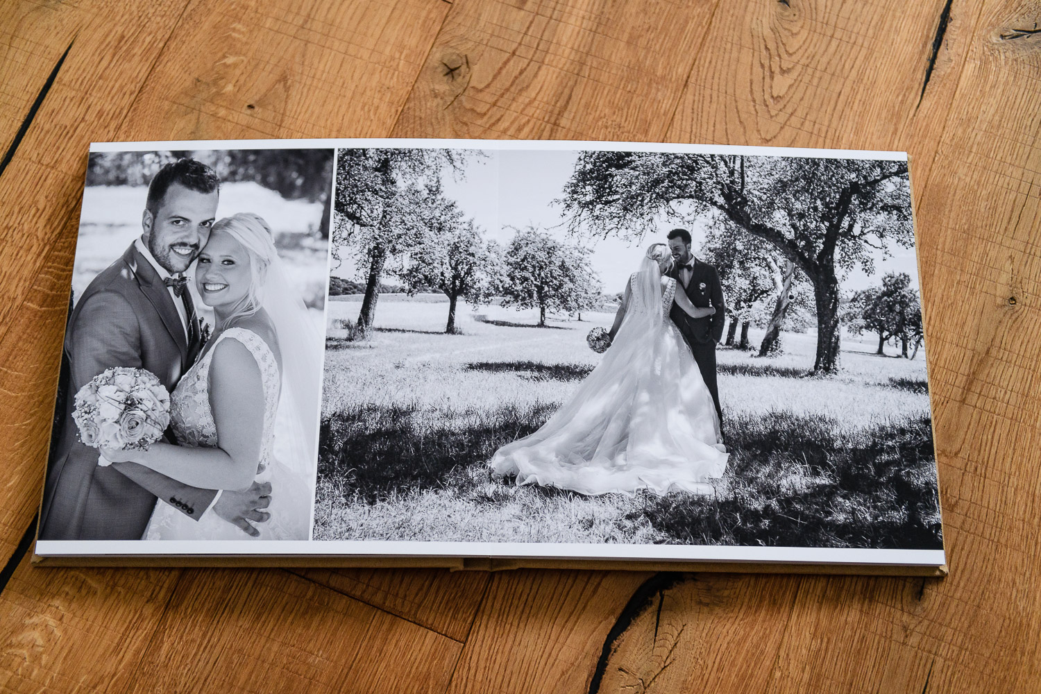 hochwertigem-Hochzeitsfotoalbum-aufgegeschlagen-auf-Holzboden-liegend